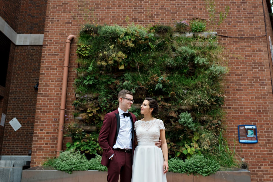 A wedding couple stand in front of a garden wall in Philadelphia.